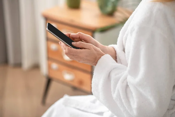Una mujer vestida con una bata blanca mandando mensajes de texto en un teléfono inteligente — Foto de Stock