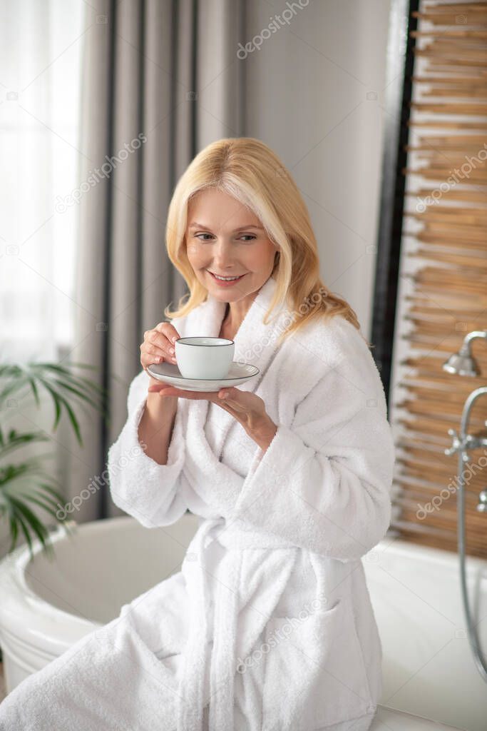 Good-looking blonde woman having tea and looking balanced