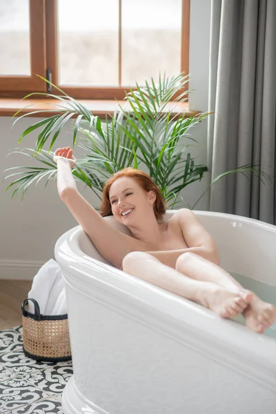 Pretty naked woman enjoying a bath and looking contented — 图库照片