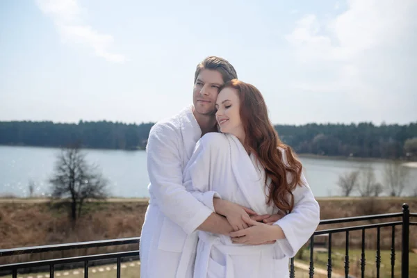A couple in white bathrobes enjoying the morning in a countryside house — Stock Photo, Image
