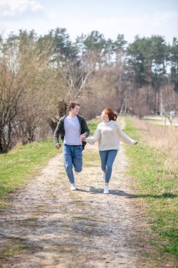 Doğada koşan erkek ve kadın el ele tutuşuyorlar