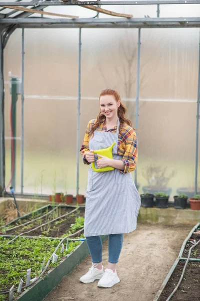 Glimlachende vrouw in schort met gieter — Stockfoto