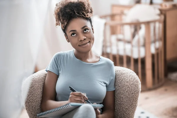 Pensamento feliz afro-americana mulher com caneta e caderno — Fotografia de Stock