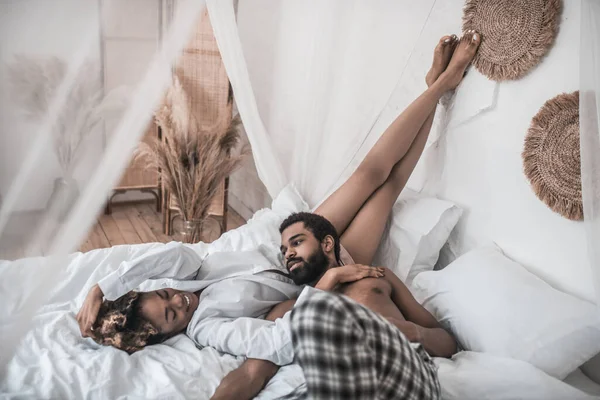 Афроамериканка и муж лежат на кровати, отдыхая — стоковое фото