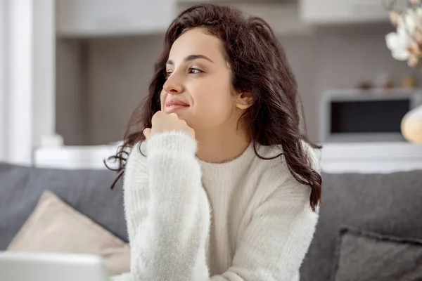 Mujer joven sentada en el sofá con un ordenador portátil y buscando relajado — Foto de Stock