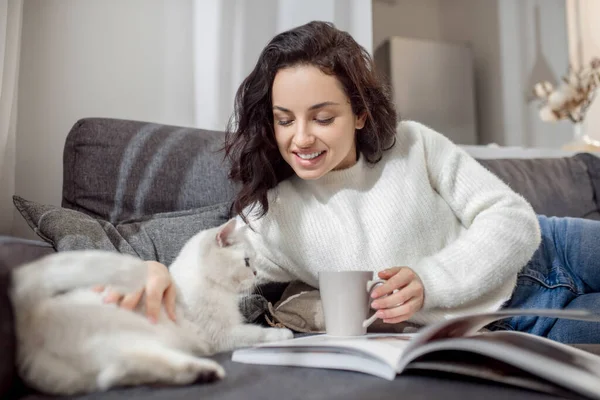 Жіночий власник домашніх тварин виглядає щасливим, проводячи час зі своєю кішкою — стокове фото