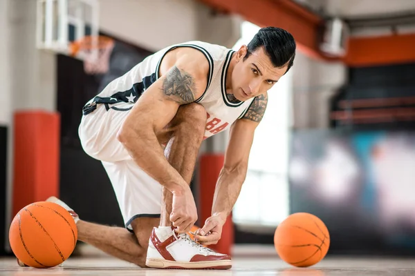 Young man with tatoo having a workout in gym and looking concentrated — Stock Photo, Image
