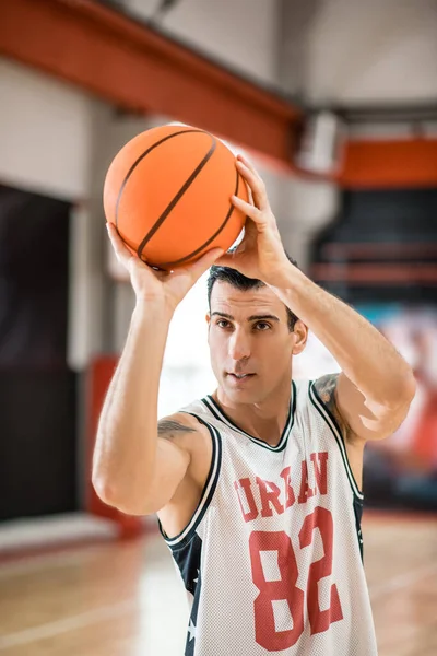 Young man with tatoo throwing a ball into a ring — Stock Photo, Image