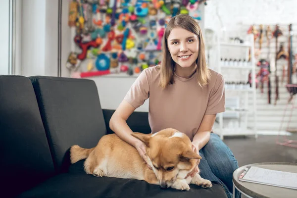 Propietaria de mascotas sentada en un sofá con su perro —  Fotos de Stock