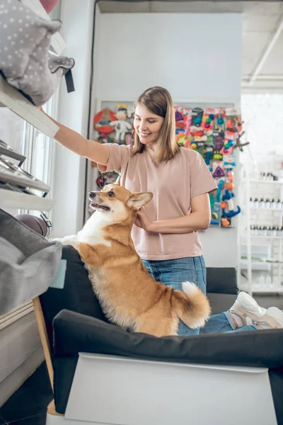 Una chica sonriente eligiendo accesorios de animales en una tienda de mascotas —  Fotos de Stock