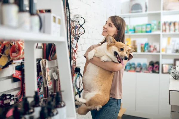 Egy boldog lány és az aranyos kutyája egy állatkereskedésben. — Stock Fotó