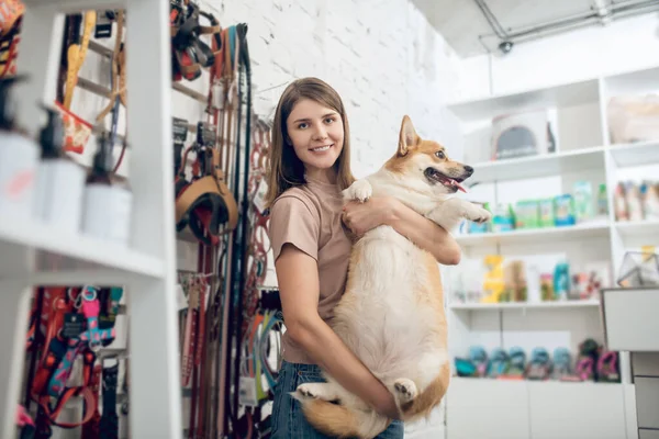 Una chica feliz y su lindo perro en una tienda de mascotas —  Fotos de Stock