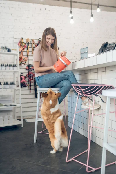 Chica joven eligiendo comida para su mascota en una tienda de mascotas —  Fotos de Stock