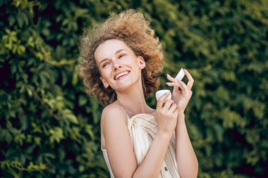 Elinde bir kavanoz organik yüz kremi olan güzel bir kadın.