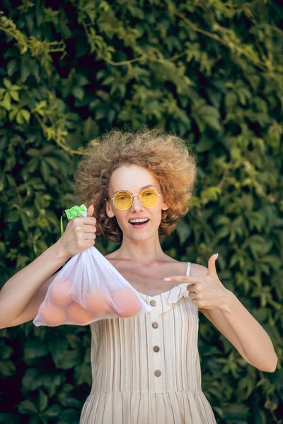 Giovane donna sorridente con una nettarine in mano sensazione incredibile — Foto Stock