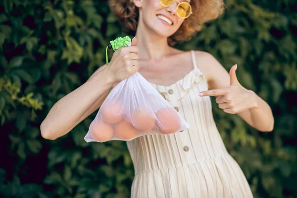 Jong glimlachen vrouw met een nectarines in haar hand gevoel geweldig — Stockfoto