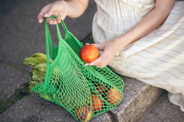 Vrouw zittend op de trap met een zak fruit — Stockfoto