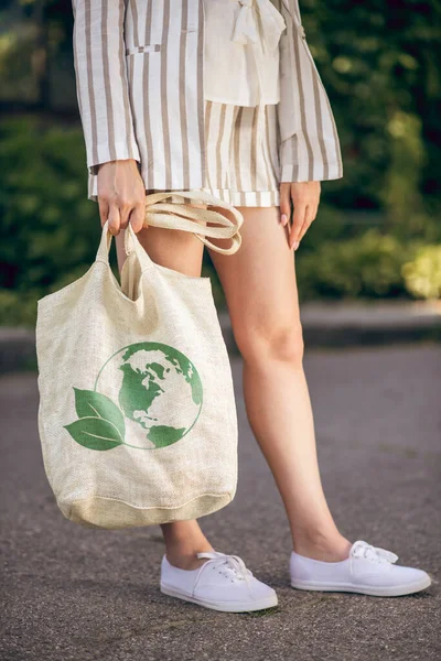 Close up picture of a woman standing in the street with eco bag in hands