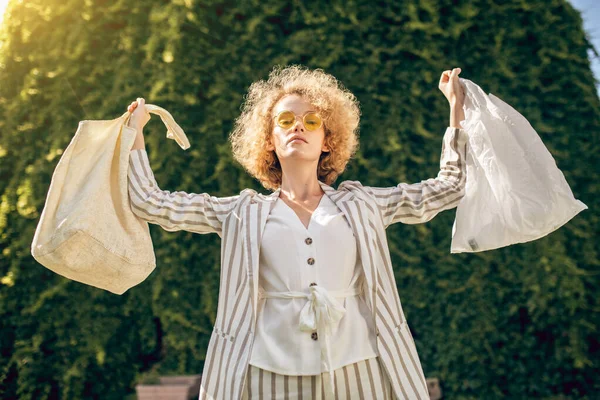 Capelli ricci giovane donna che tiene due borse in mano — Foto Stock