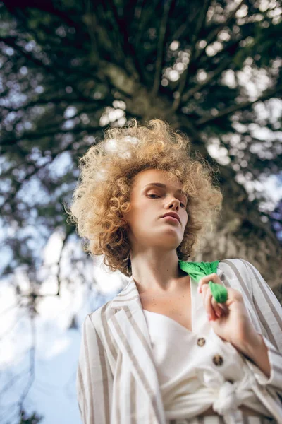 Lockigt hår ung kvinna i en park ser omtänksam — Stockfoto