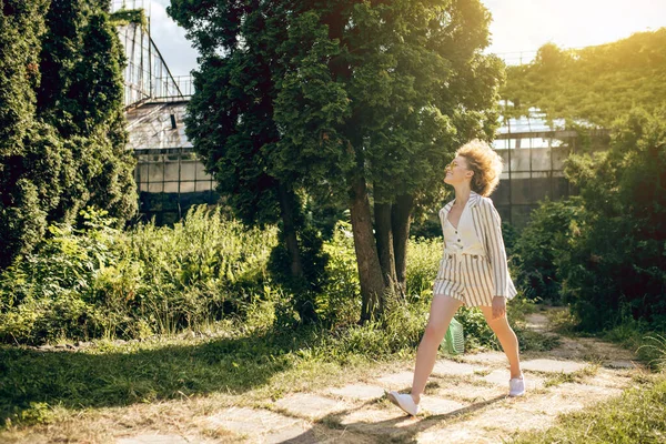 Lockigt hår ung kvinna promenader i solen — Stockfoto