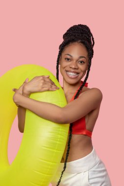 Güzel Afrikalı Amerikalı kadın elinde sarı bir tüp tutuyordu ve eğleniyordu.