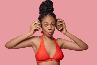 Koyu tenli kadın hindistan cevizi tutuyor ve eğleniyor.