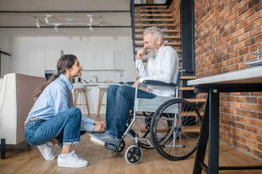 Dark-haired young woman helping her handicapped husband to tie his snickers