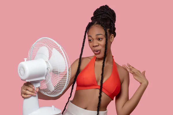 Smiling african american woman holding a fan looking tired from heat — Stock Photo, Image