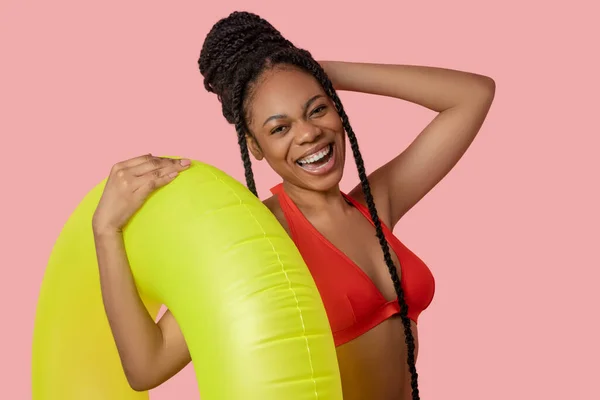 Smiling african american woman holding a yellow tube — Stock Photo, Image