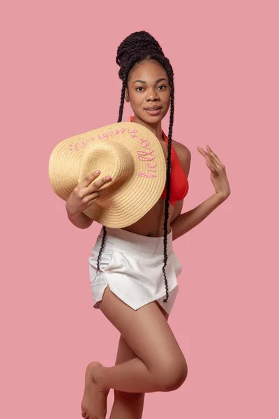Pretty african american woman with a straw hat in hands — Stock Photo, Image