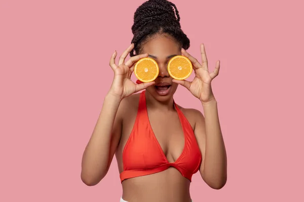 Joven mujer afroamericana con rodajas de naranja en las manos — Foto de Stock