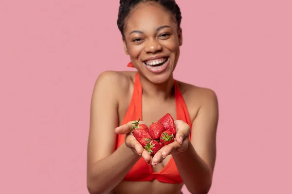 Mulata em laranja top segurando morangos em suas mãos — Fotografia de Stock