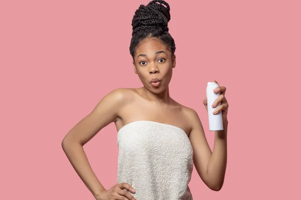 Dark-skinned young woman spraying deodorant on her body after shower — Stock Photo, Image