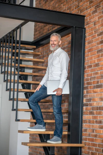 Высокий мужчина среднего возраста, стоящий на лестнице — стоковое фото