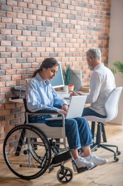 Handicapped young woman working with her colleague in the office