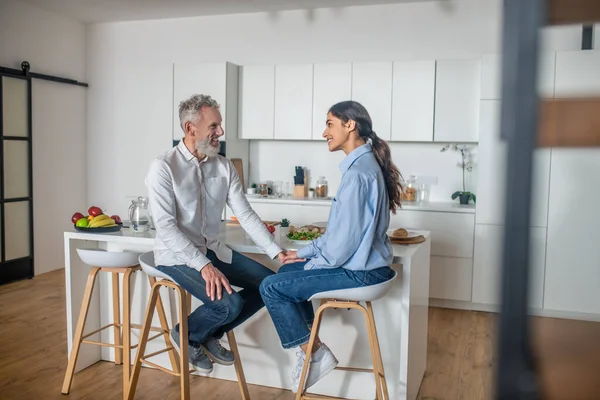 Dark-haired young woman feeding her husband and smiling — Stok fotoğraf