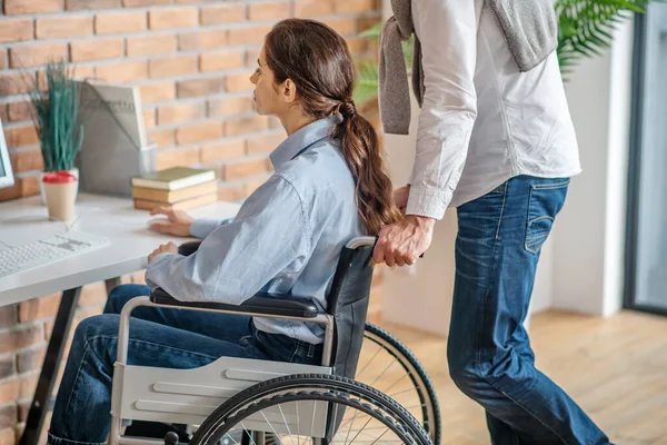Een man die gehandicapte jonge vrouwen helpt om aan tafel te komen — Stockfoto