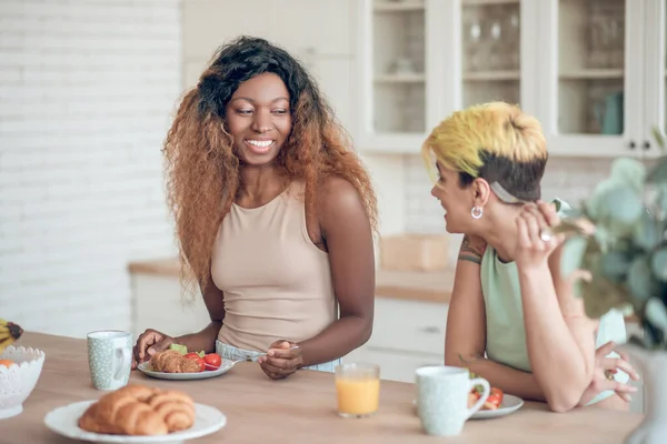 Riendo mujer de piel oscura y novia durante el desayuno —  Fotos de Stock