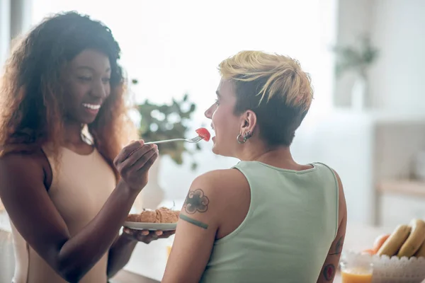 暗いです肌の女性給餌caucasianガールフレンドとともにトマト — ストック写真