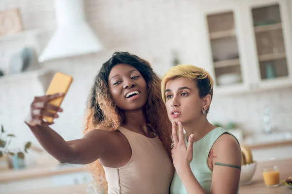 Donkere vrouw met smartphone in uitgestrekte hand en vriendin — Stockfoto
