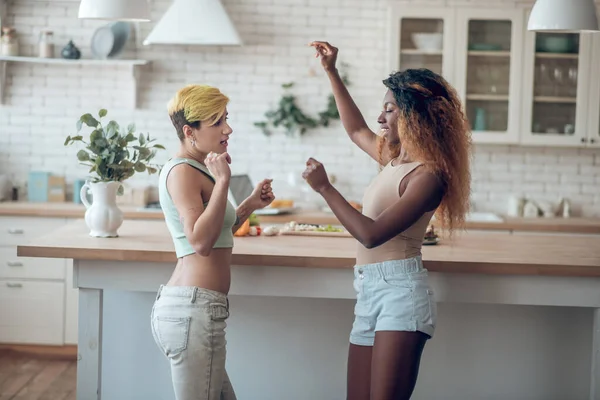 Днем две девушки танцуют на кухне — стоковое фото