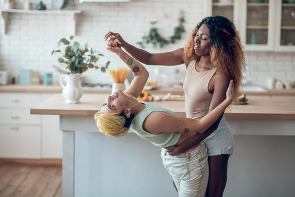 Donna dalla pelle scura che sostiene la ragazza caucasica nella danza — Foto Stock