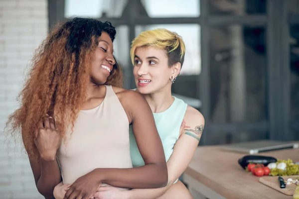 Blank vrouw knuffelen van achter donker gevild vriendin — Stockfoto