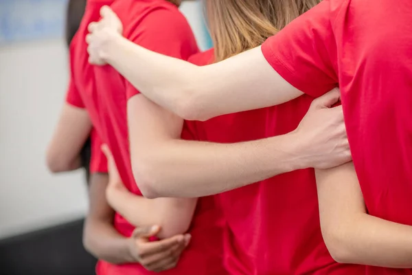 Hände umarmen Ehrenamtliche im roten T-Shirt — Stockfoto