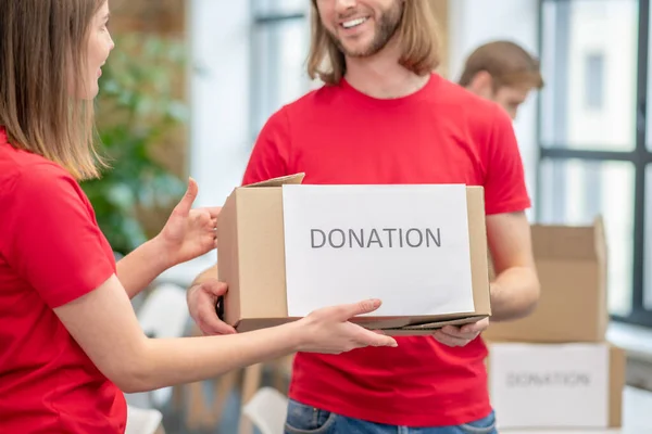 Tipo sosteniendo empacado caja de donación a chica — Foto de Stock