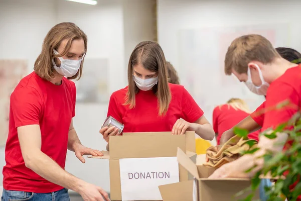 Dobrovolníci nosí ochranné masky balení dárcovských krabic — Stock fotografie