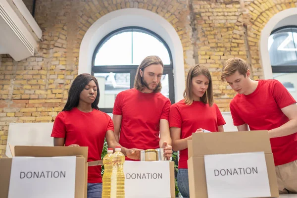 Studenti dobrovolníci balení dárcovské krabice společně — Stock fotografie