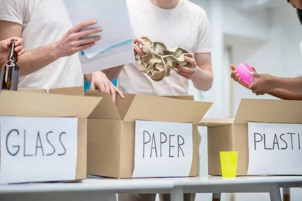 Ungdomar sorterar skräp i lämpliga lådor — Stockfoto