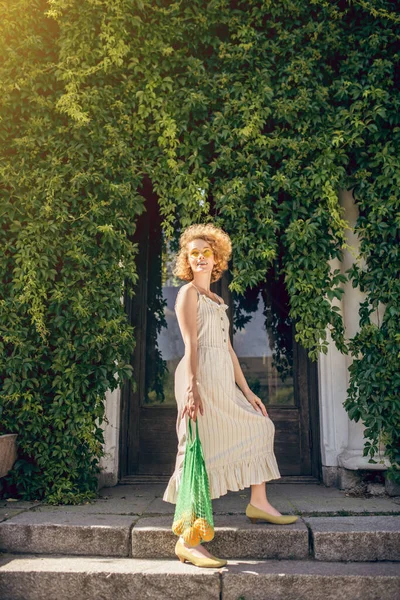 Immagine di una giovane donna vestita di bianco con una borsa a rete con frutta in mano — Foto Stock